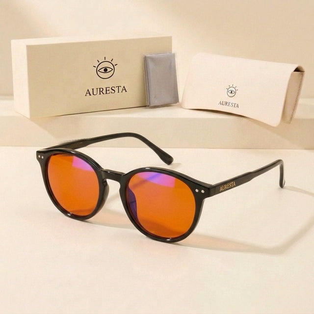 Raven black round blue light glasses beside an Auresta gift box, cleaning cloth and soft case on beige