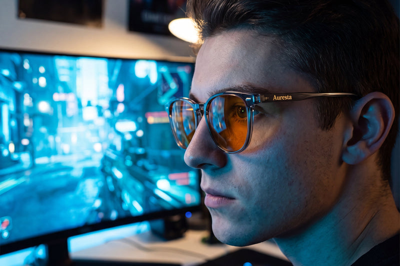 Gamer wearing Auresta Aura blue light glasses with amber lenses at a gaming setup