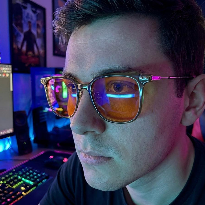 Close-up of a gamer wearing Olive blue light glasses at a neon-lit desk, orange lenses catching screen glow